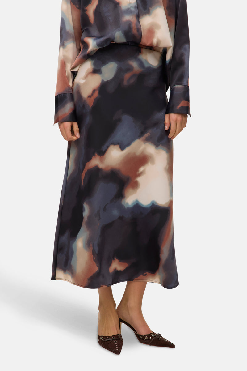 Multikleurige lange rok van VERO MODA, abstract patroon, met een paar bruine pumps met kleine strikjes.