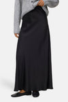 Black long flowing skirt with smooth satin-like texture, worn with gray sweater and black flat shoes, front view