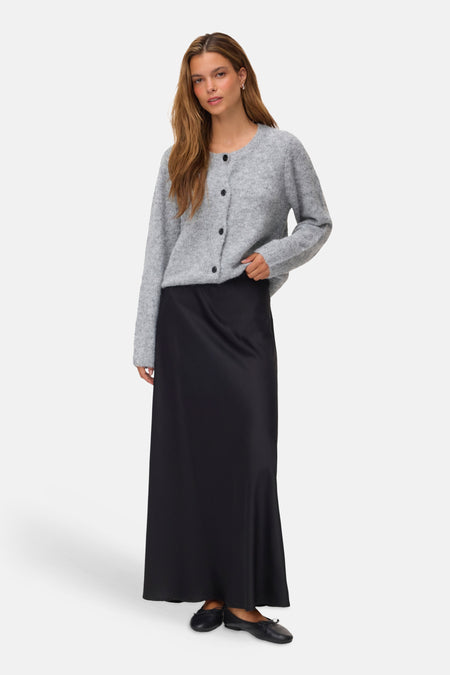 Black long skirt with smooth satin finish, full-length silhouette, paired with gray cardigan and black flats in front view