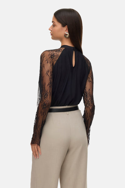 Zwart VERO MODA®-blouse met lange kanten mouwen en een druppelvormige sluiting aan de achterkant, gedragen met een riem en een beige broek.