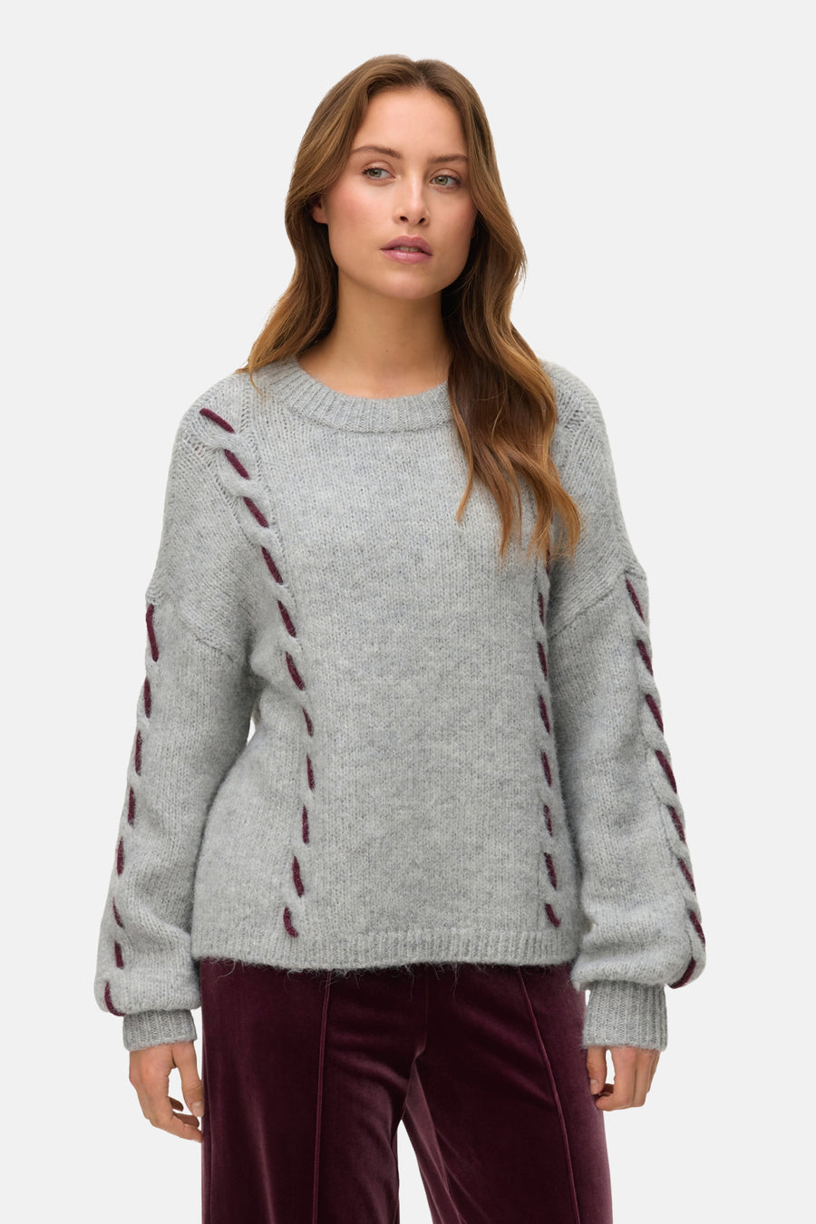 Grijze trui met ronde hals van VERO MODA, met bordeauxrode stikseldetails op de mouwen en zijkanten.