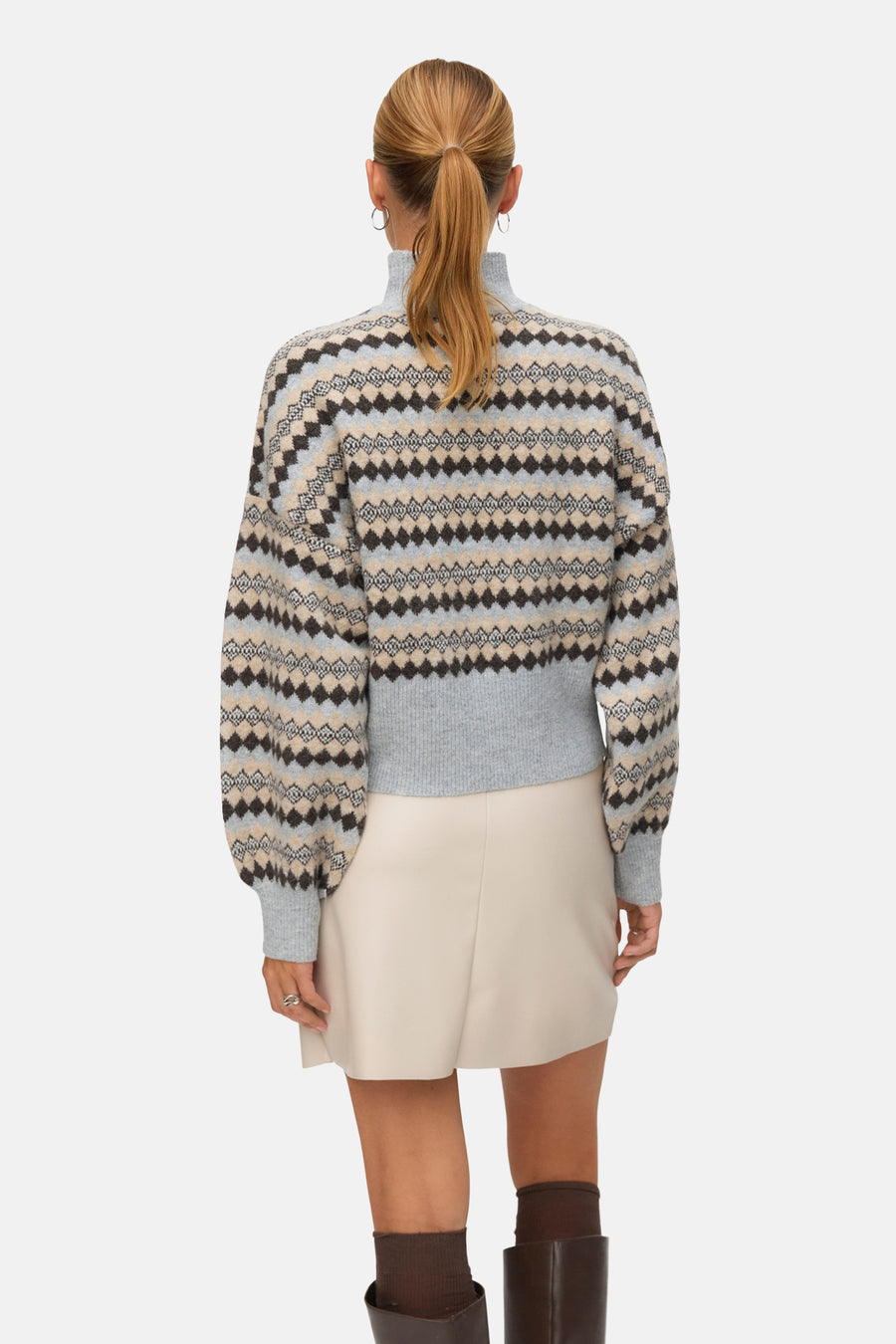 Pull à col roulé multicolore de VERO MODA®, motif géométrique losanges, porté avec une jupe et des bottes marron.