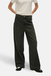 Gekleurde groene jeans van Vero Moda, gedragen met een wit T-shirt en zwarte lakleren schoenen.