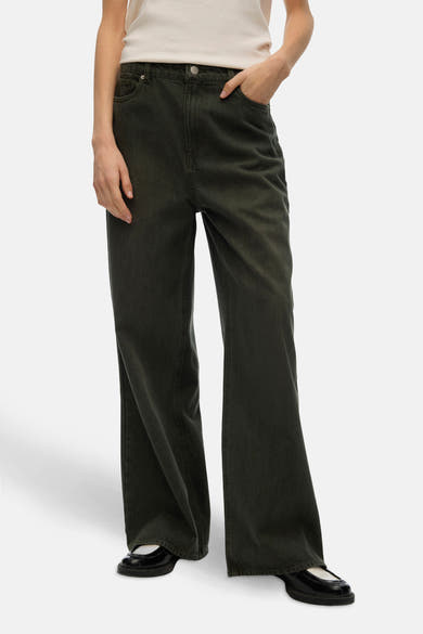 Gekleurde groene jeans van VERO MODA, losse pasvorm, gedragen met een gebroken wit T-shirt en zwarte platte schoenen.