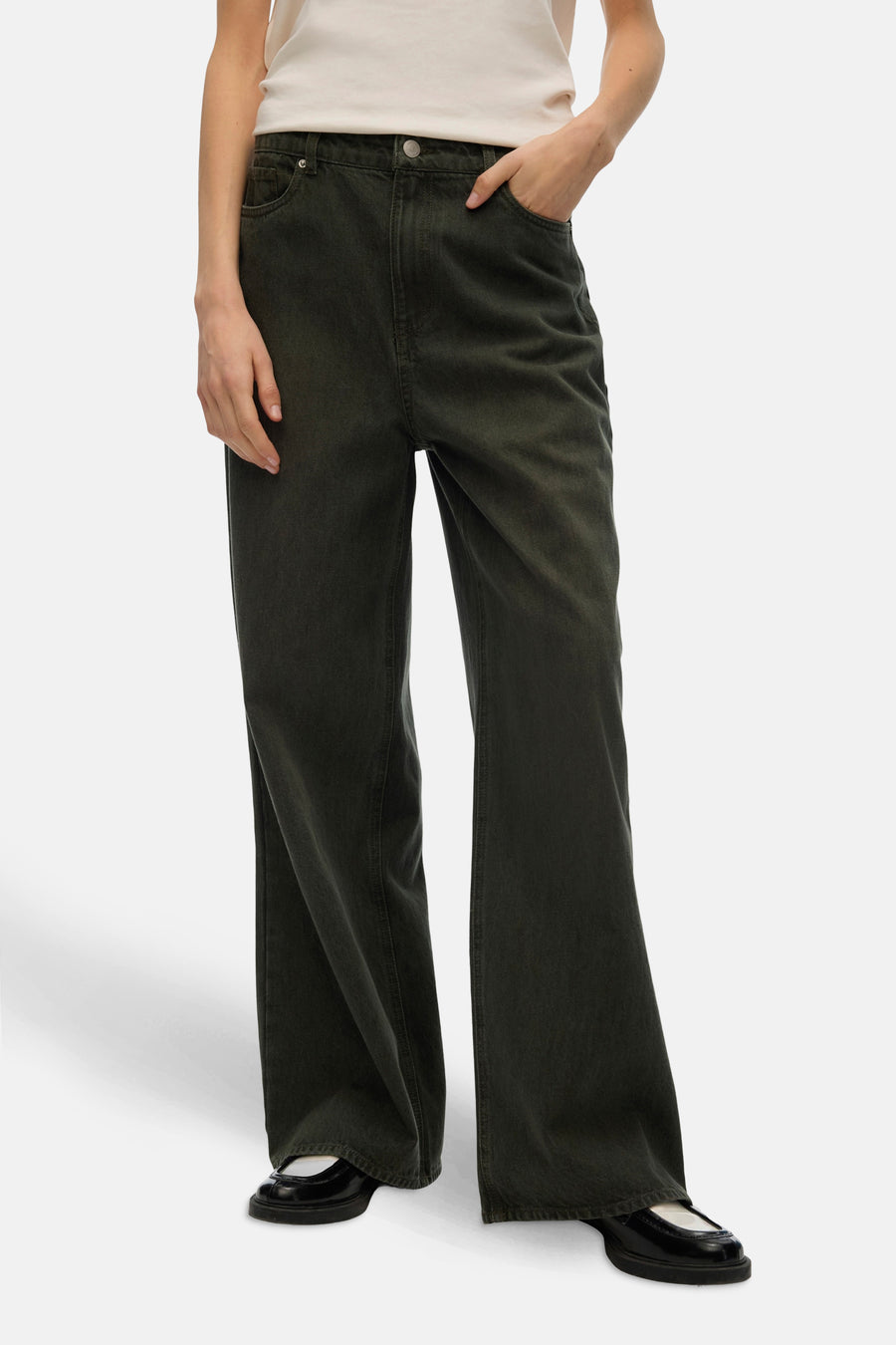 Gekleurde groene jeans van VERO MODA, losse pasvorm, gedragen met een gebroken wit T-shirt en zwarte platte schoenen.