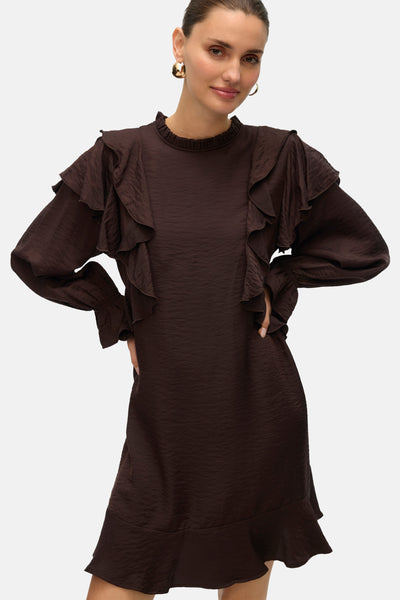 Robe marron à manches longues de VERO MODA, avec des volants décoratifs et des boucles d'oreilles dorées.