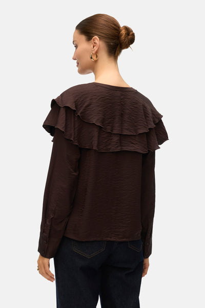 Bruin overhemd met lange mouwen van Vero Moda, met decoratieve ruches op de rug, gedragen met een spijkerbroek.