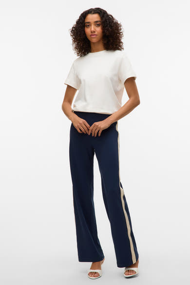Pantalon bleu marine à rayures latérales crème par VERO MODA®, porté avec un t-shirt blanc et des mules blanches.