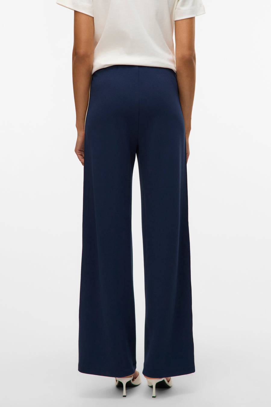 Pantalon bleu marine de Vero Moda, coupe ample et jambes larges, porté avec un haut blanc et des escarpins.