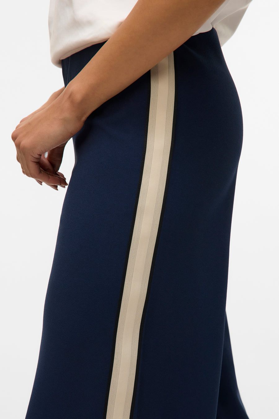 Pantalon bleu marine avec bande latérale contrastée de Vero Moda, porté avec un haut blanc.