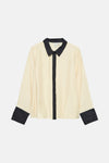 Beige overhemd met lange mouwen van VERO MODA, met zwarte kraag en manchetten, op een effen achtergrond.