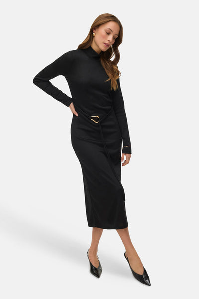Robe noire de VERO MODA, avec ceinture dorée et chaussures à talons noirs.
