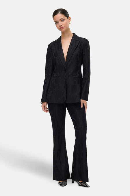 Zwarte jacquard blazer van Vero Moda, gedragen met een bijpassende broek en pumps met parels.