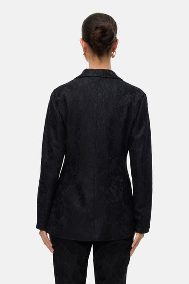 Zwarte blazer van VERO MODA met textuurpatroon, getailleerde kraag en aansluitende pasvorm, van achteren gezien.