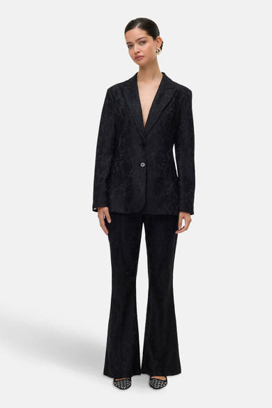 Zwarte broek van VERO MODA® met toon-op-toon bloemenpatroon, uitlopende pijpen en glitter schoenen.