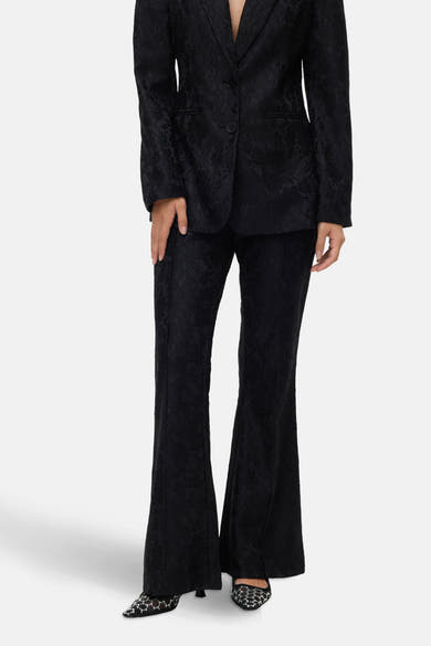 Zwarte uitlopende broek van VERO MODA met textuurpatroon, gedragen met versierde schoenen.