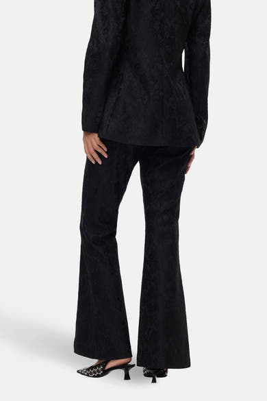 Zwarte broek met bloemenprint van VERO MODA, uitlopende pasvorm, gedragen met spitse pumps.