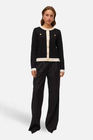 Zwart gilet van VERO MODA, met een crèmekleurige bies en gouden knopen, gedragen met een wijde zwarte broek.