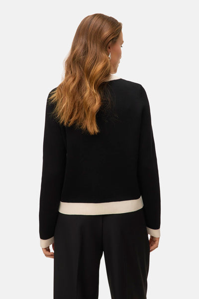 Zwarte bodywarmer van VERO MODA met contrasterende ivoorkleurige bies, gedragen met een effen zwarte broek.