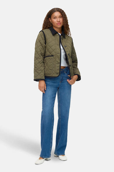 Kort groen jasje van VERO MODA, met doorgestikt patroon en zwarte afwerkingen, gedragen met een blauwe jeans.