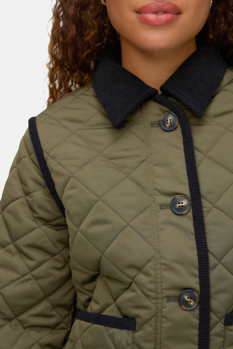 Korte groene jas van VERO MODA met ruitvormig doorgestikt patroon en zwarte corduroy afwerkingen.