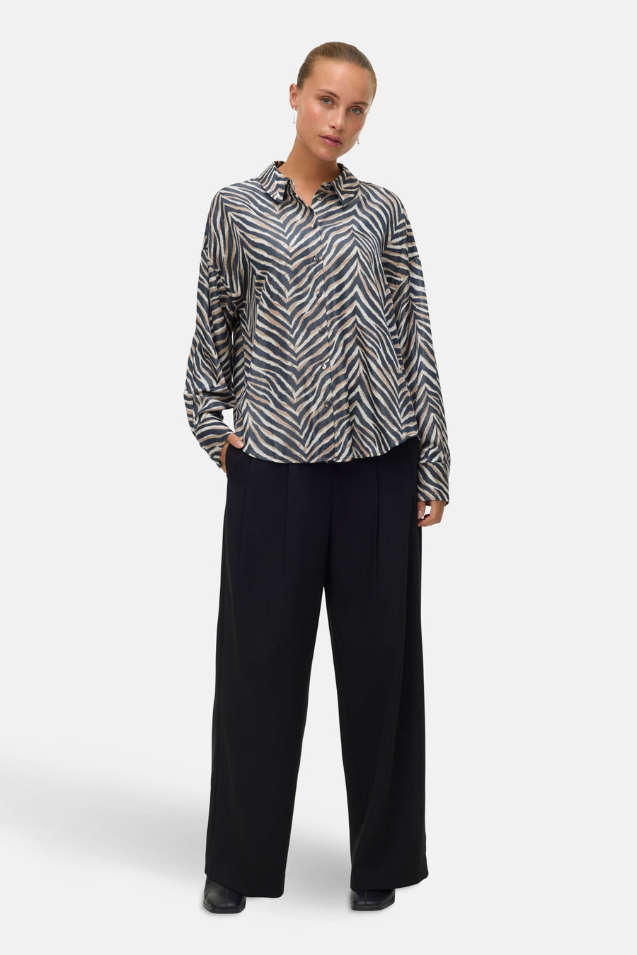 Chemisier à manches longues multicolore de VERO MODA, motif zébré porté avec un pantalon noir à jambes larges.
