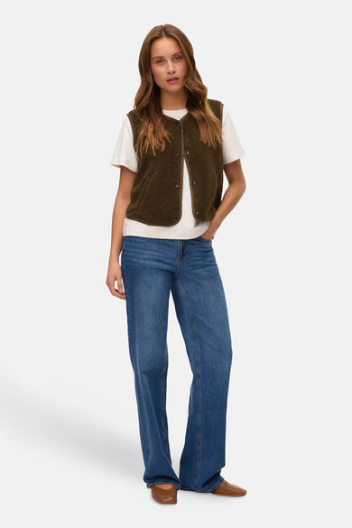 Groen fleecevest van Vero Moda, gedragen over een wit T-shirt met een uitlopende blauwe jeans en bruine schoenen.