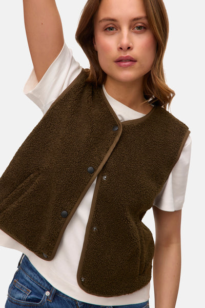 Groen sherpa gilet van VERO MODA, gedragen over een wit T-shirt en een blauwe jeans.