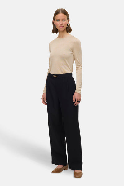 Beige T-shirt met lange mouwen van VERO MODA, met zwarte broek met hoge taille en bruine schoenen.