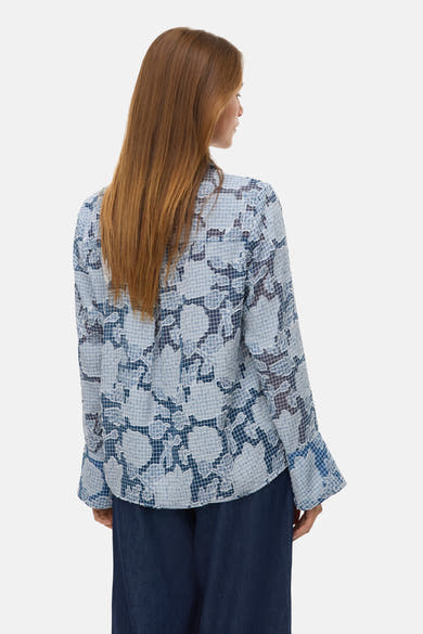 Chemisier bleu à manches longues de Vero Moda, avec un motif floral à carreaux, porté avec un pantalon foncé.
