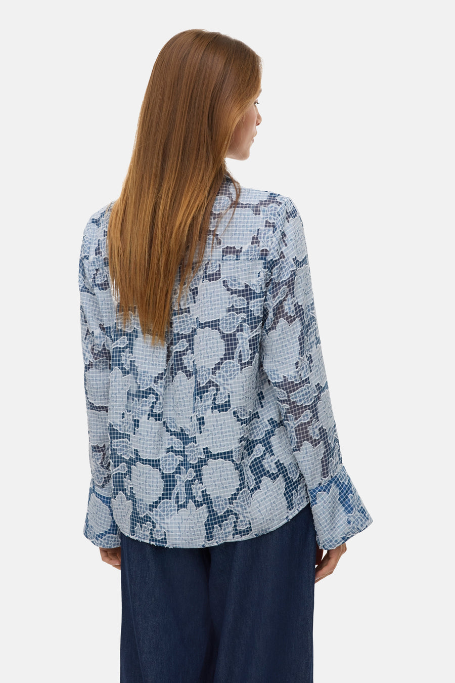 Chemisier bleu à manches longues de Vero Moda, avec un motif floral à carreaux, porté avec un pantalon foncé.
