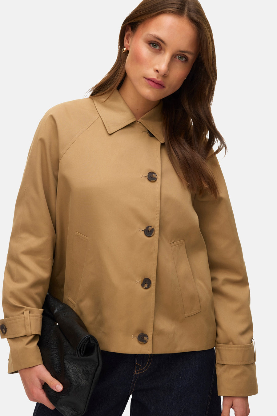 Veste courte beige de VERO MODA, avec boutons marron, poches et tenant une pochette noire.