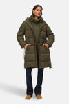 Veste longue verte de VERO MODA, portée avec un pull vert, un jean bleu et des chaussures marron.