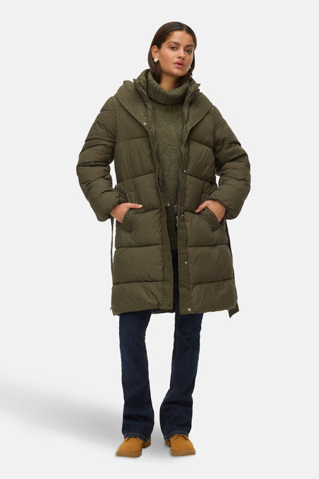 Lange groene jas van VERO MODA, met capuchon, strikceintuur en gedragen met een blauwe jeans en bruine laarzen.