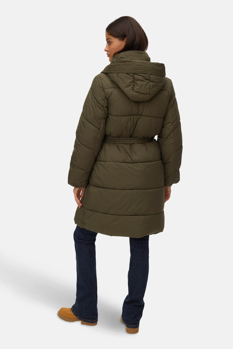 Veste longue verte par VERO MODA, avec capuche, ceinture à nouer et portées avec un jean bleu et des bottes marron.