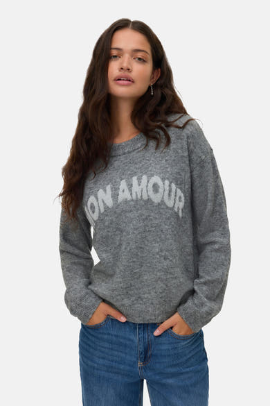 Grijze trui met ronde hals van VERO MODA, met witte letters, gedragen met een blauwe jeans.