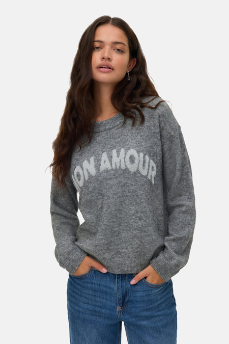 Grijze trui met ronde hals van VERO MODA, met witte letters, gedragen met een blauwe jeans.