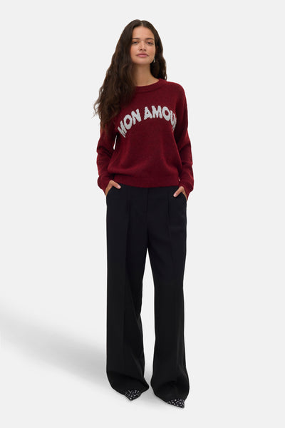 Rode trui met ronde hals van VERO MODA, met witte opdruk, gedragen met een zwarte wijde broek.