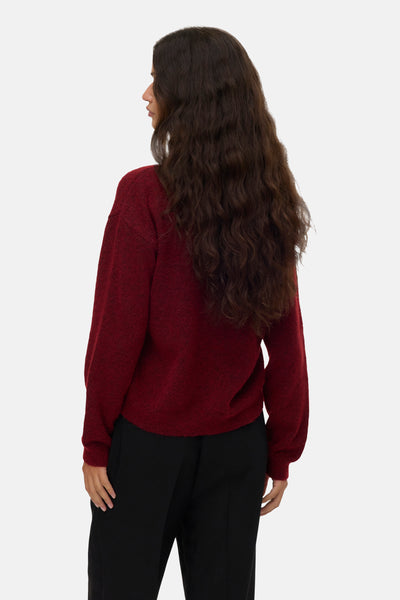 Rode trui met ronde hals van VERO MODA®, lange mouwen en een relaxte pasvorm, gedragen met een zwarte broek.