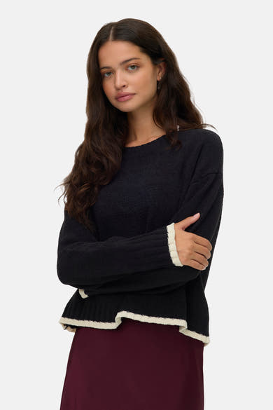Pull à col rond noir de VERO MODA, avec détails côtelés blancs au bord des manches et à la base.