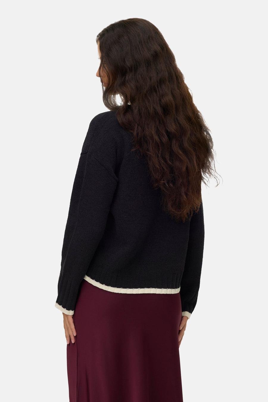 Pull à col rond noir de VERO MODA, avec un bordure contrastante et une jupe bordeaux.