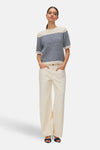 Pull à col rond bleu rayé de VERO MODA, porté avec un pantalon blanc et des sandales bleu foncé.