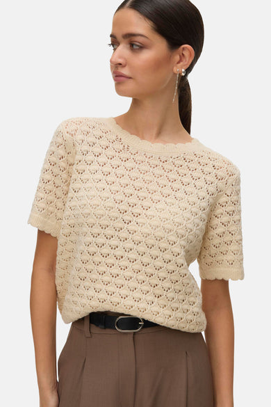 Beige T-shirt met korte mouwen van VERO MODA, in open gebreide stof, gedragen met een bruine broek met hoge taille.