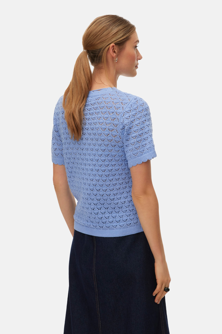 T-shirt bleu à manches courtes de VERO MODA, en maille ajourée, porté avec une jupe foncée.