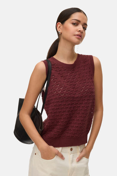 Débardeur brique en maille ajourée de VERO MODA, porté avec un pantalon blanc et un sac noir.