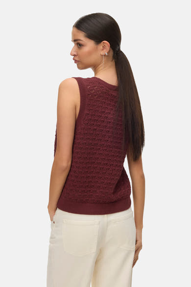 Débardeur brique de VERO MODA®, avec motif ajouré et porté avec un pantalon blanc.
