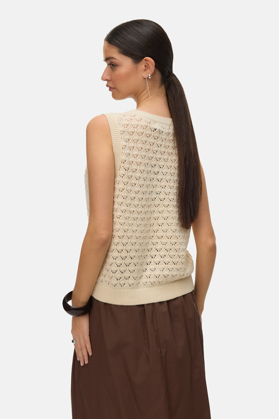 Débardeur écru de VERO MODA, maille ajourée portée avec une jupe marron et un bracelet foncé.
