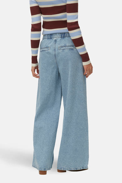 Jean large en denim bleu clair de VERO MODA, avec taille élastiquée et poches arrière plaquées.