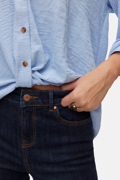 Chemise à manches longues bleue claire de VERO MODA®, nouée sur le devant avec boutons marron.