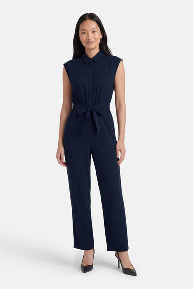 Combinaison bleue de VERO MODA® sans manches, col chemise et taille nouée, portée avec des escarpins noirs.